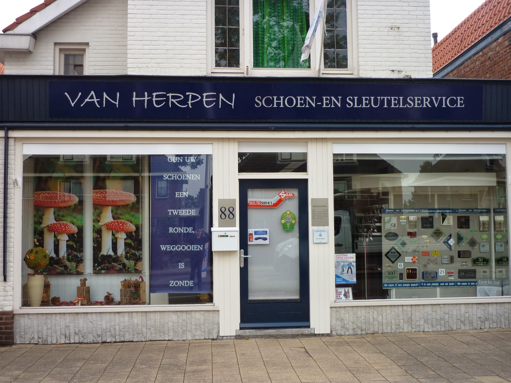 De winkel van Van Herpen schoen- en sleutelservice aan de Axelsestraat 88 in Terneuzen, met de blauwe gevelbalk en de tekst in de etalage