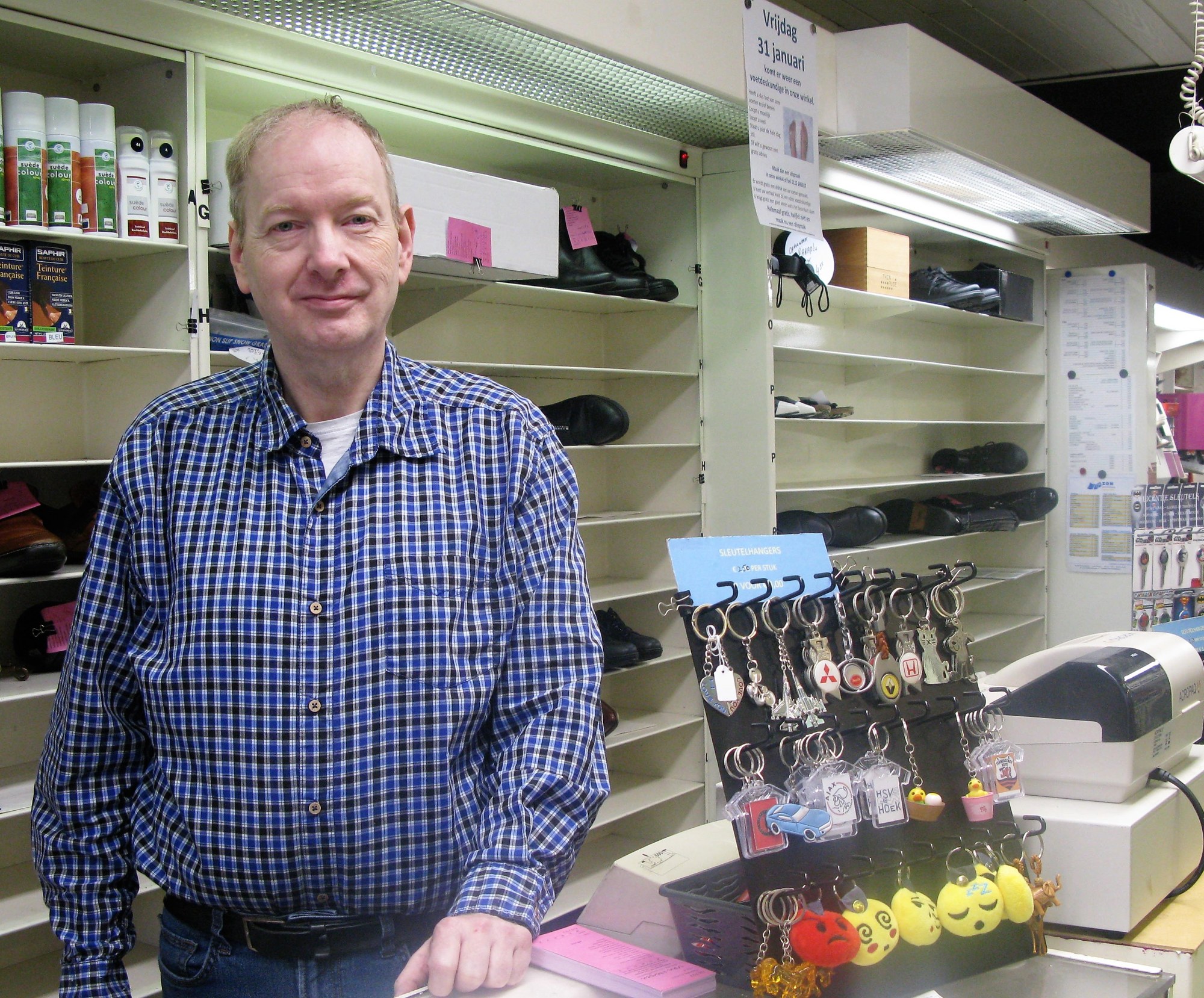 Ron van Herpen achter de toonbank, naast de sleutelhangers en de sleutelmachine